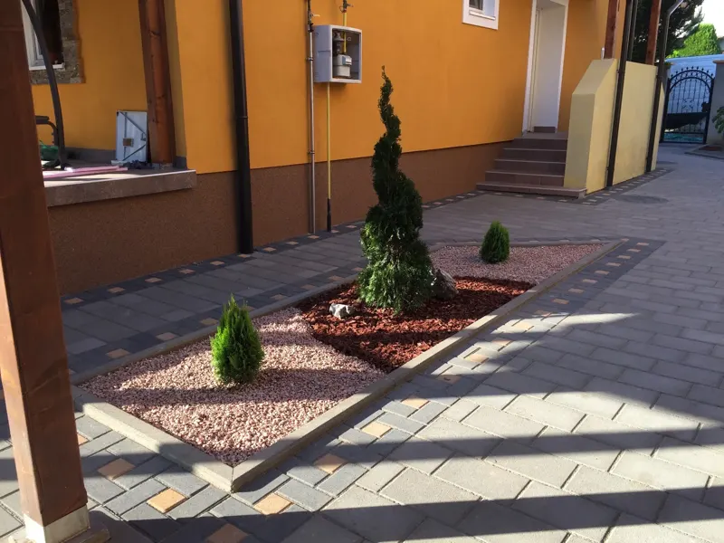 Popločana staza kroz uređeno dvorište sa mostićem